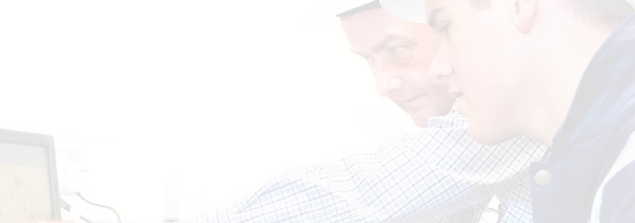 Senior and junior engineers discussing work together in office, senior man pointing at screen