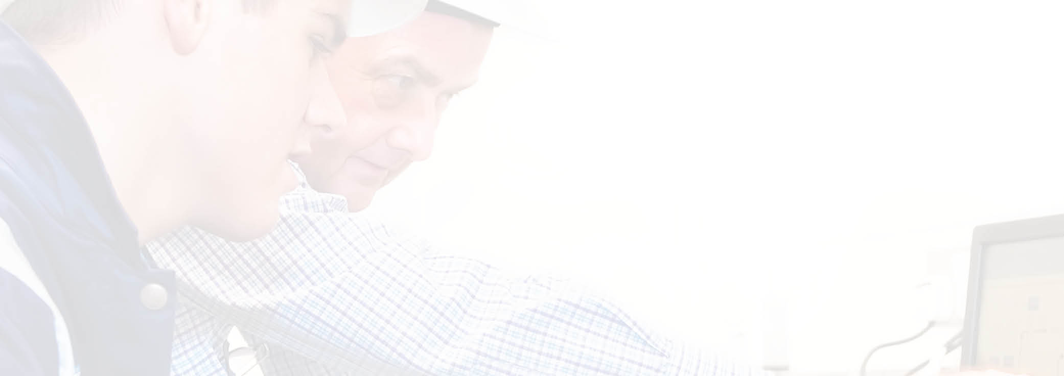 Senior and junior engineers discussing work together in office, senior man pointing at screen