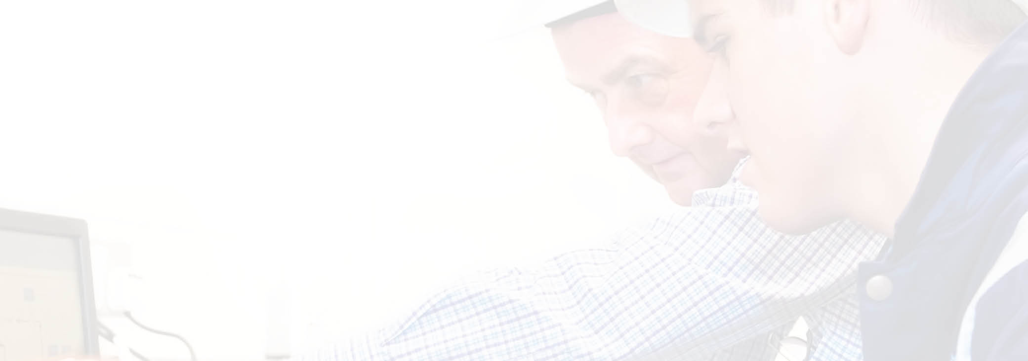 Senior and junior engineers discussing work together in office, senior man pointing at screen